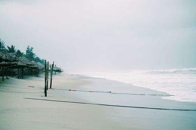 Wooden posts at beach against sky