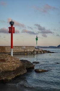 Lighthouse by sea against buildings and sky