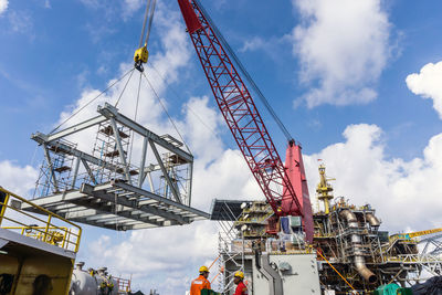 Low angle view of crane at construction site against sky