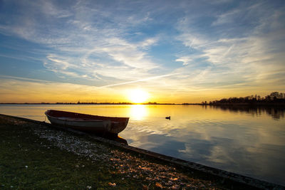 Boat moored on sea against sky during sunset