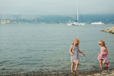 Women standing by sailboat against sea