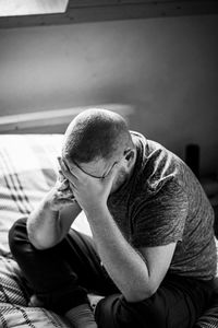 Midsection of man sitting at home on the bad