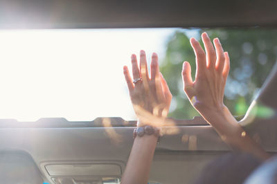 Cropped image of woman with arms raised in car