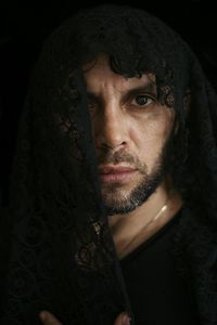 Close-up portrait of serious man against black background