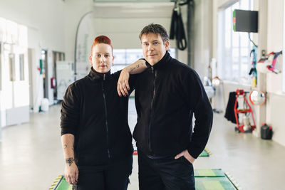 Portrait of confident mechanics standing in auto repair shop