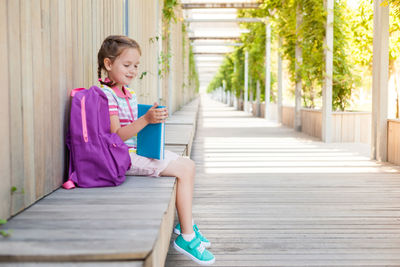 Side view of girl sitting on mobile phone