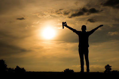 Silhouette man standing on land against sky during sunset