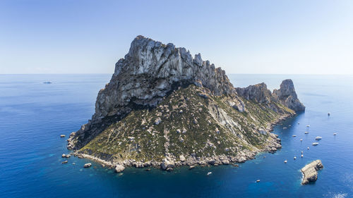 Scenic view of rock formation in sea against clear sky