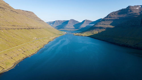 Scenic view of lake and mountains against clear blue sky