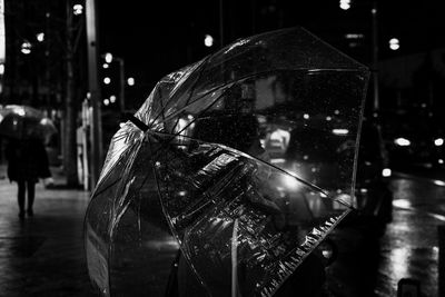 Woman wearing mask holding umbrella while standing on road at night