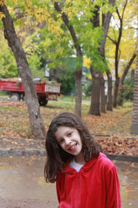 Portrait of young woman standing on tree trunk