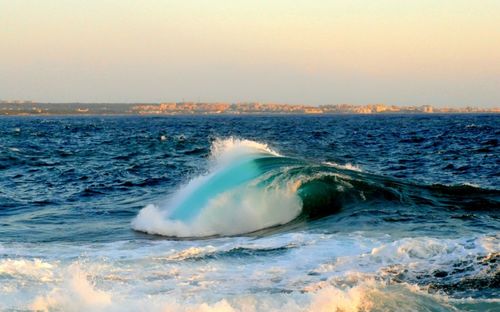 Waves splashing in sea against clear sky