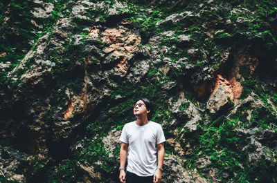 Man looking away while standing against rock formation