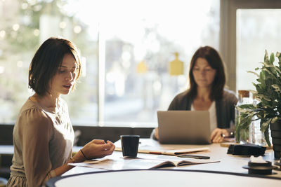 Businesswoman working at desk against window in office