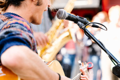 Selective focus on a face of a man singing and playing a guitar in the street