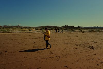 Full length of man running on beach against clear sky