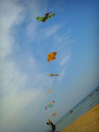 Multi colored balloons against cloudy sky