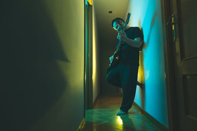 Caucasian man playing electric guitar at home. colorful lighting.