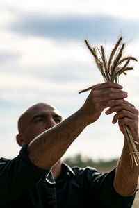 Man holding plants against sky