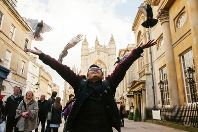 Man raising arms while birds flying against church