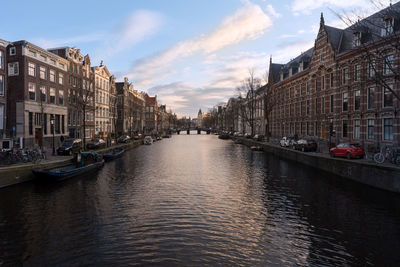 Canal amidst buildings in city against sky