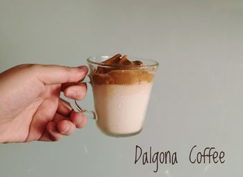 Midsection of person holding drink against glass over white background