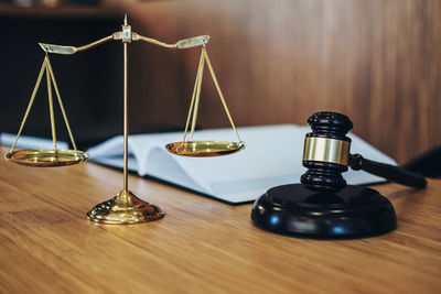 Close-up of gavel and weight scale on wooden table in courtroom