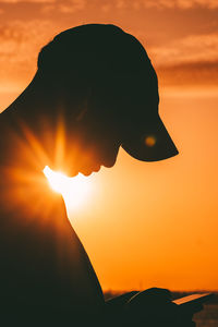 Silhouette woman with arms raised against sky during sunset