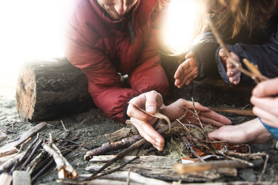 Group of people lighting up a fire on the beach with small pieces wood