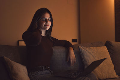 Young woman sitting on sofa at home