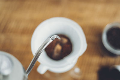 Directly above shot of coffee pouring in cup on table