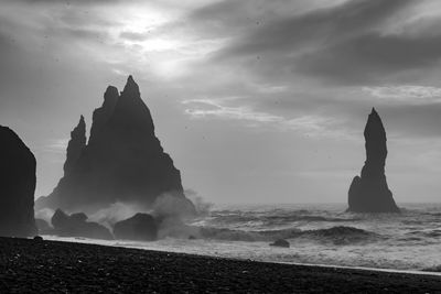 Rock formation on beach against sky