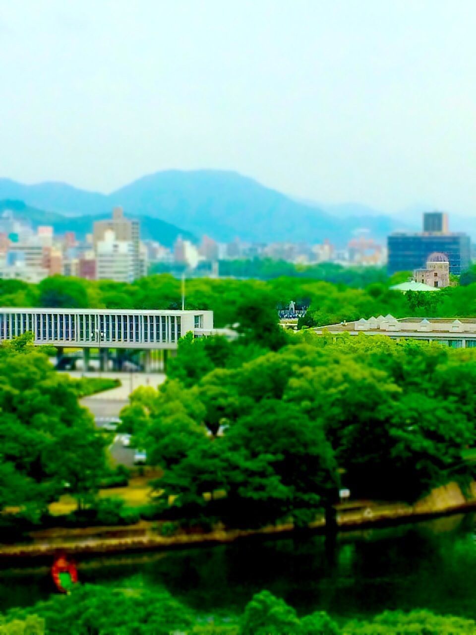 tree, built structure, architecture, clear sky, mountain, building exterior, water, green color, growth, river, nature, beauty in nature, tranquility, tranquil scene, sky, day, outdoors, plant, scenics, landscape