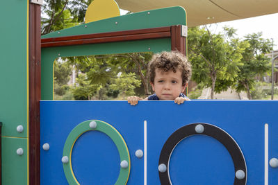 Curious boy with curly hair playing outdoors.