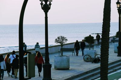 People at sea shore against clear sky