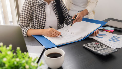 Midsection of woman using laptop on table