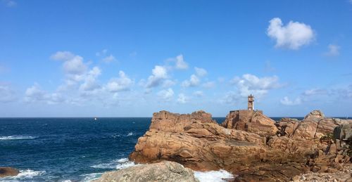 Rock formations on beach against blue sky