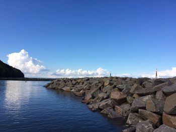 Rocks by sea against blue sky