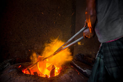 Low section of man working on bonfire