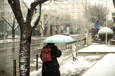Rear view of woman on wet street during winter