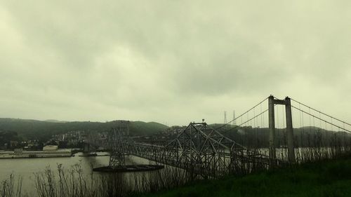 Bridge over river against cloudy sky