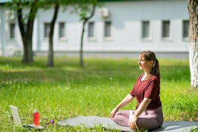 Woman sitting on field against plants