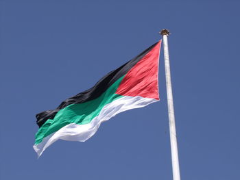 Low angle view of flag against clear blue sky