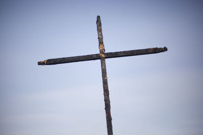 Burnt cross on a blue background. two daughters covered with coal. religious symbol. 