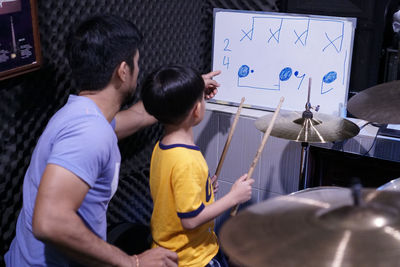 Man teaching drum to boy in class