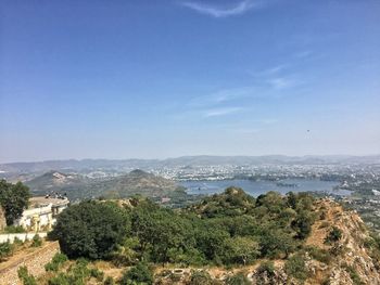 Scenic view of landscape and sea against blue sky