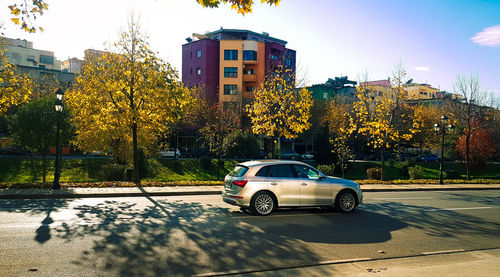 Car on street by buildings during sunny day