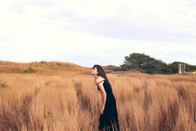 Rear view of woman standing on field against sky