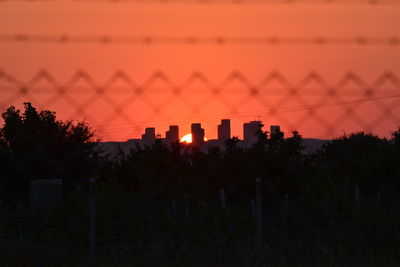 Silhouette trees and buildings against sky during sunset