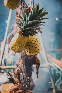 Close-up of fruit and roasted chicken hanging for sale at store